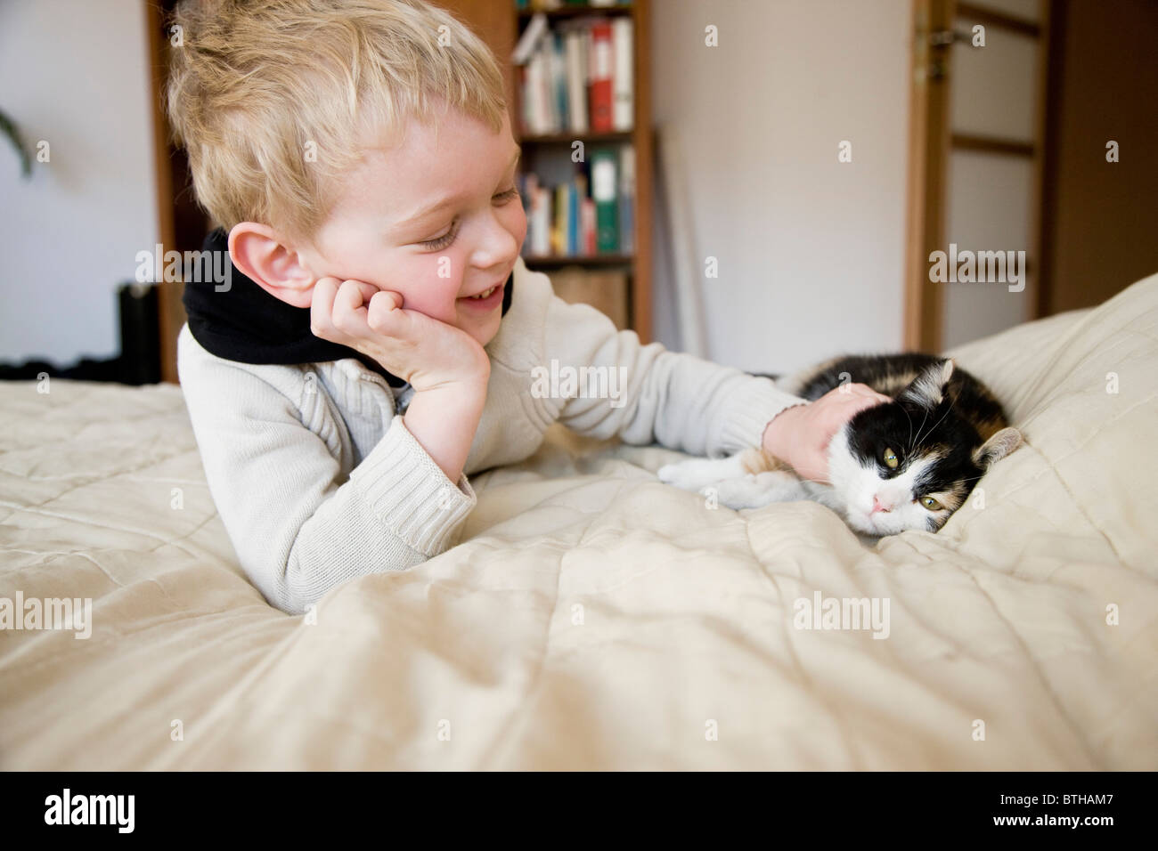Niño jugando con cat en la cama Foto de stock