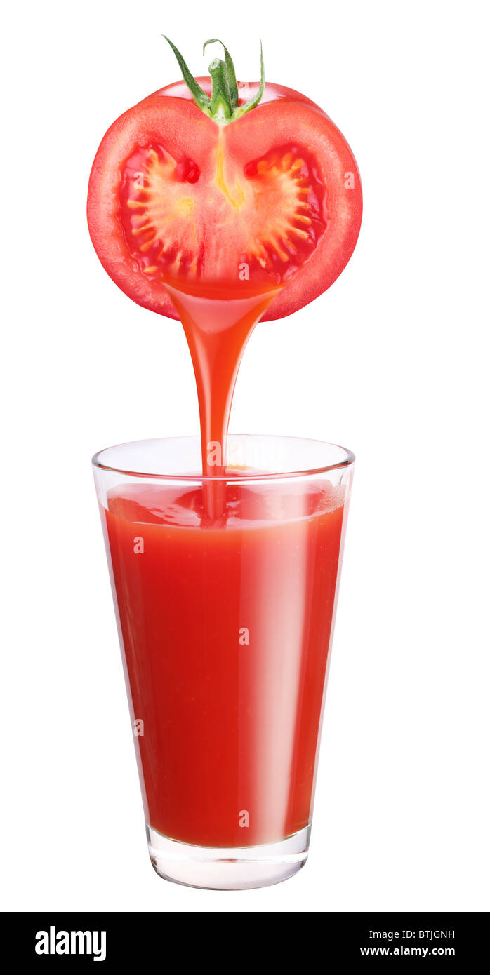 Jugo fluye desde el tomate en el vaso. Foto de stock