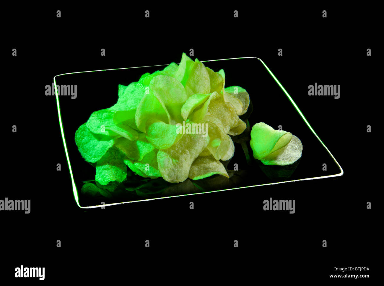 Patatas fritas chips wasabi verde en la placa negra comida basura