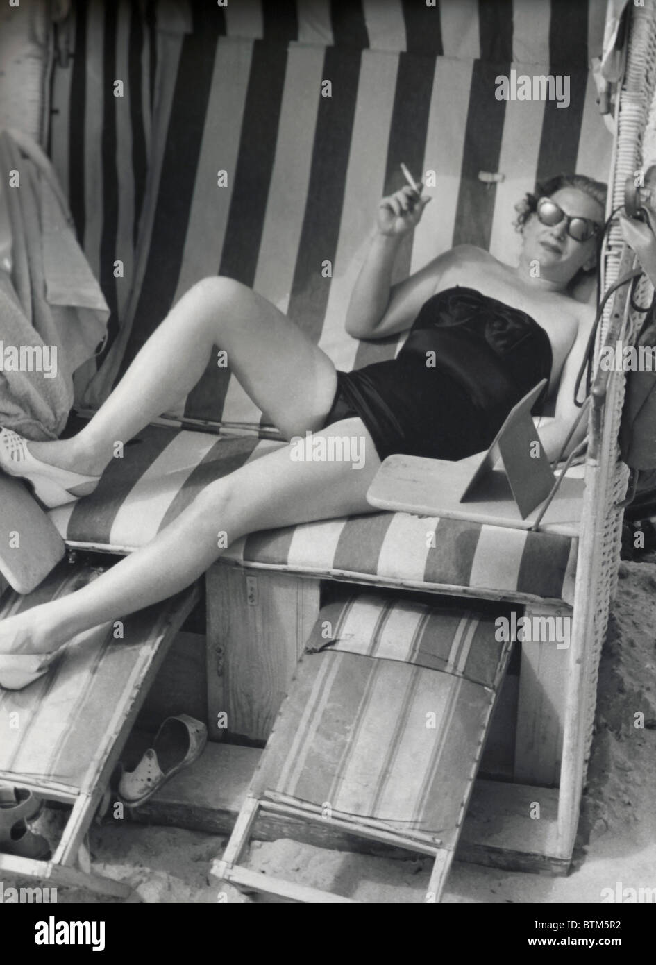 Foto histórica (1910) de una mujer sentada sobre una silla de playa Foto de stock