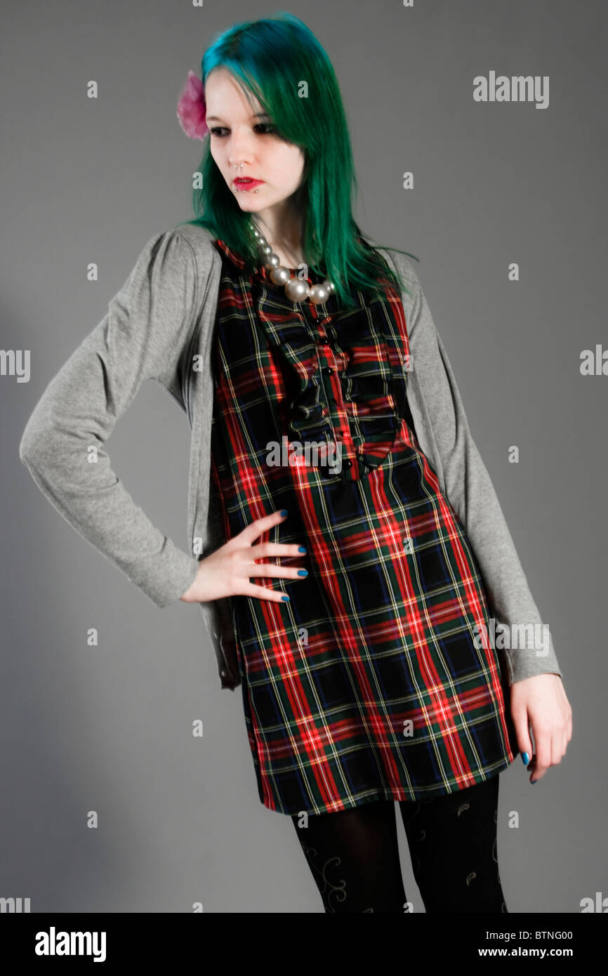 Una joven mujer goth con cabello verde en un vestido de raso y chaqueta  sobre un fondo gris! Fotografía de stock - Alamy