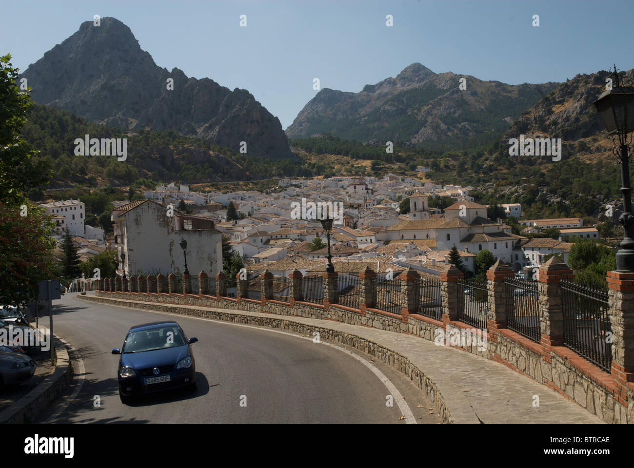España, Andalucía, Grazalema, coche moviéndose en la carretera con el pueblo y las montañas en el fondo Foto de stock