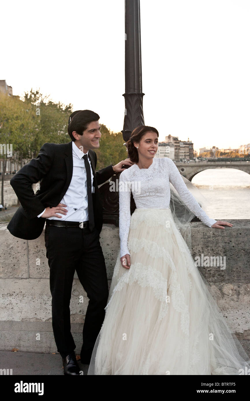 Hermosa joven novia judía con guapo novio plantea para la boda retrato contra el telón de fondo intemporal del Río Sena & bridge Foto de stock