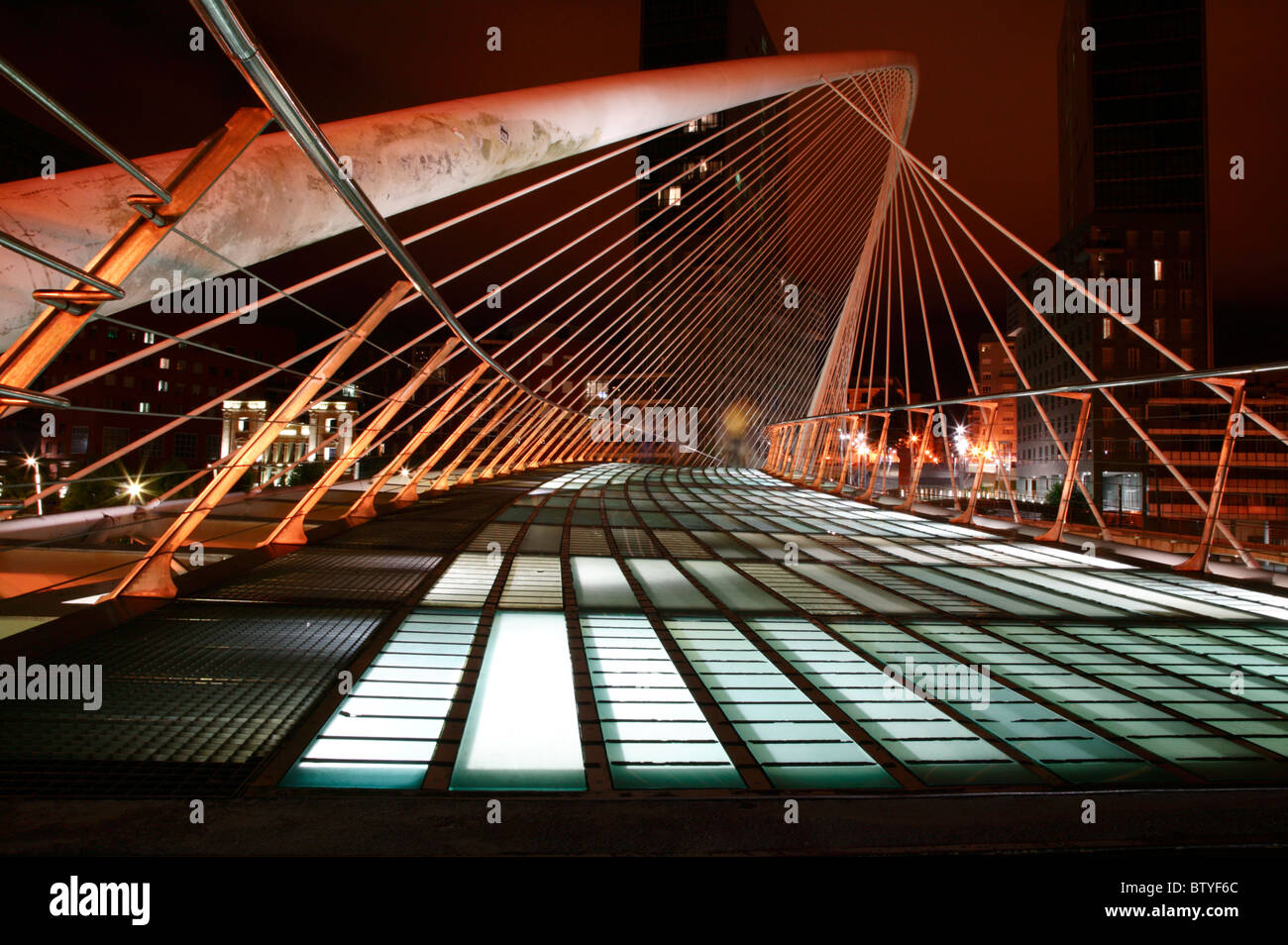 La noche, bajo el ángulo de visión, una imagen del Puente Zubizuri cruzando el río Nervión en Bilbao, España. Foto de stock