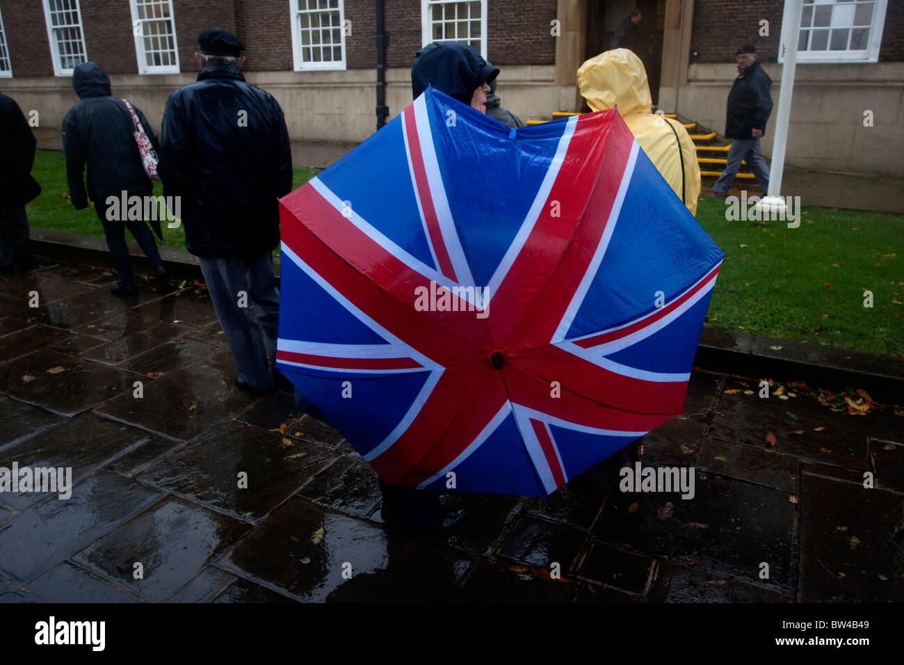 Dos señoras refugio bajo un paraguas Union Jack en Heavy Rain en Worthing, West Sussex, Reino Unido. Foto de stock