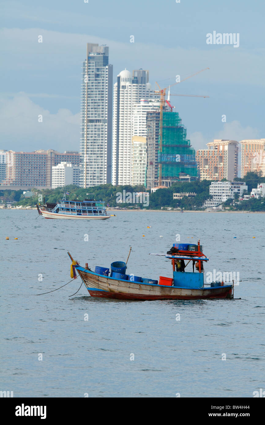 Pequeños barcos de pescadores en el mar contra edificios modernos de Pattaya, Tailandia, octubre de 2010 Foto de stock