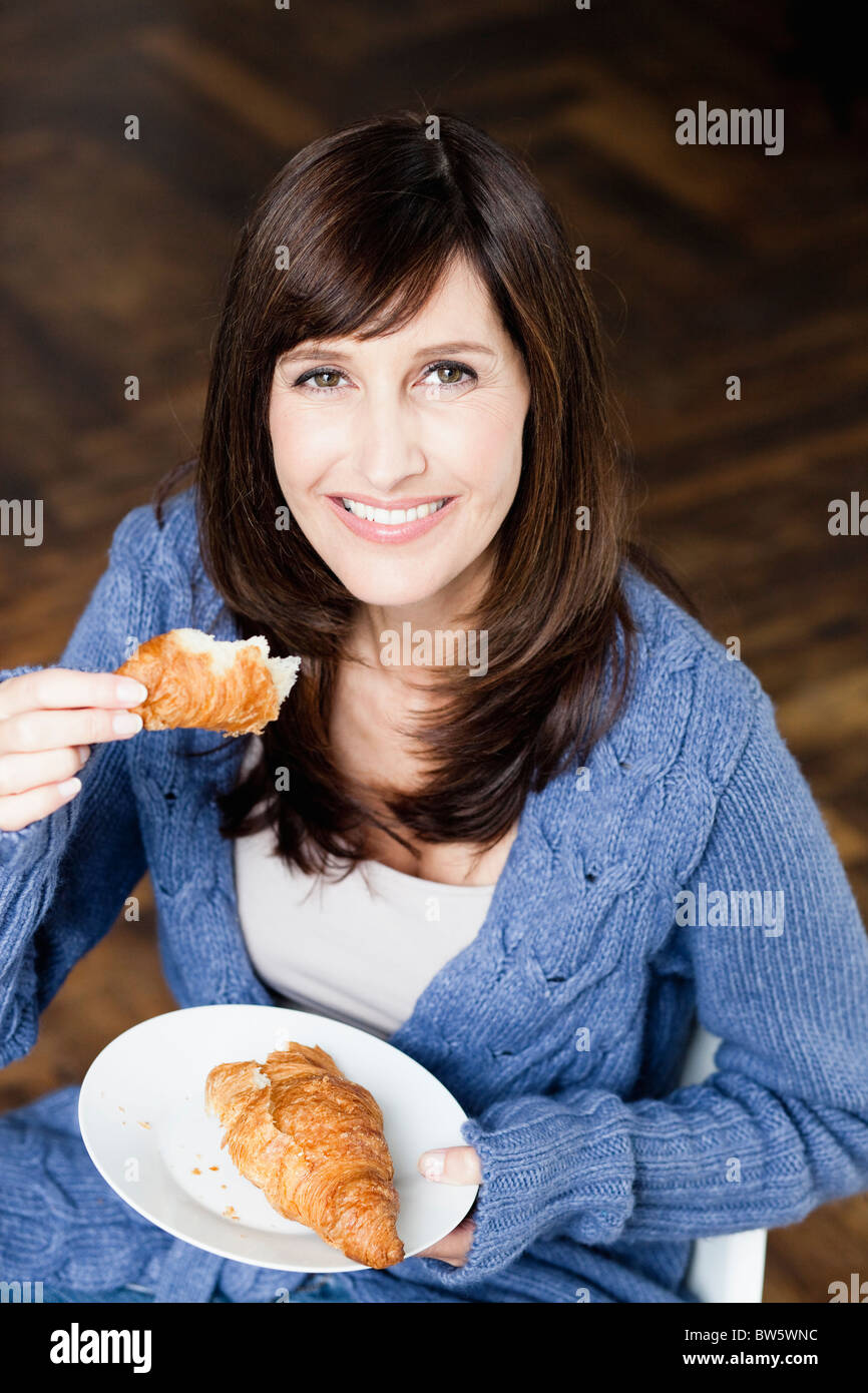 Mujer comiendo croissant Foto de stock