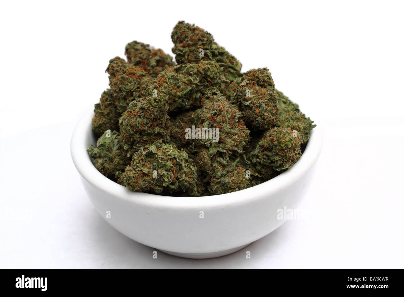 La marihuana ( Cannabis ) Bud cerca mostrando tricomas detallada y rojo pelos sobre fondo blanco aislado en tazón blanco Foto de stock