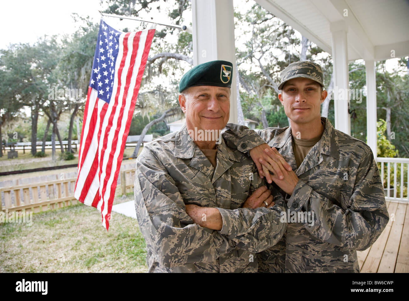 Padre e hijo en uniformes militares por bandera americana Foto de stock