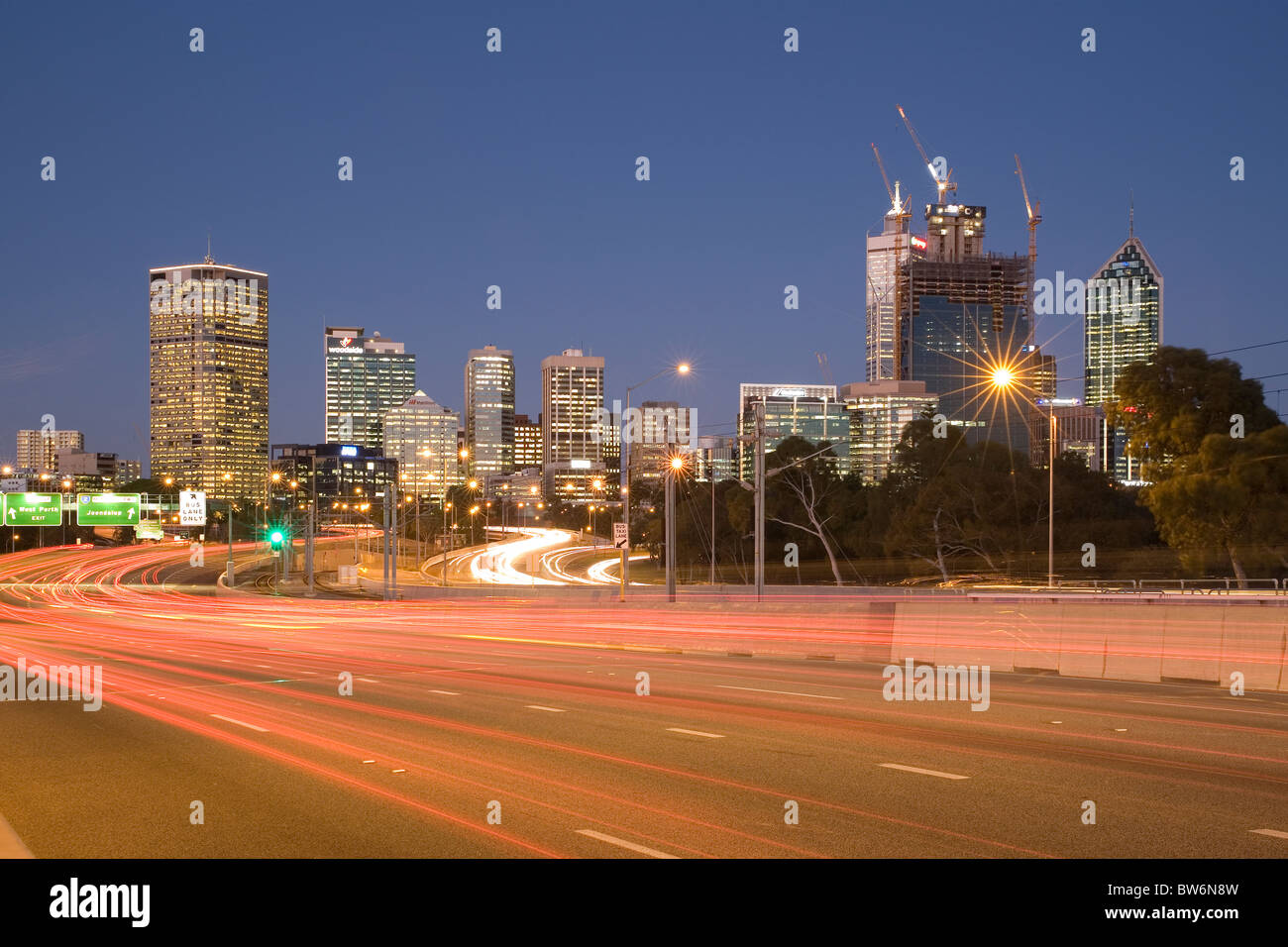 Estelas de luz en la autopista Mitchell con la ciudad de Perth, Australia Occidental, en el fondo Foto de stock