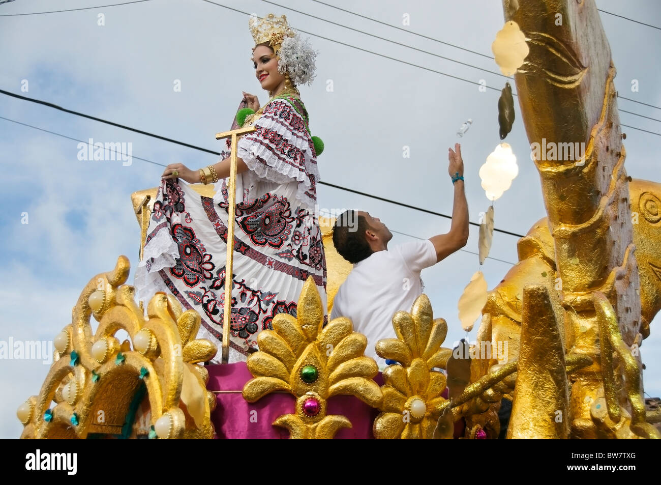 Mientras que la reina baila sobre una elaborada flotar un hombre lanza botellas miniatura de ron a la multitud en Pedasí Panamá. Foto de stock