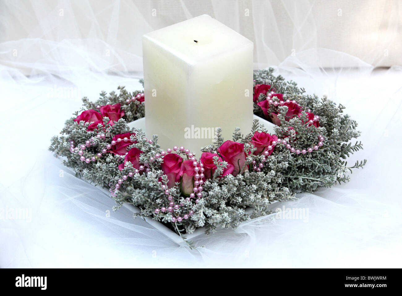 Arreglo floral con vela sobre blanco Foto de stock