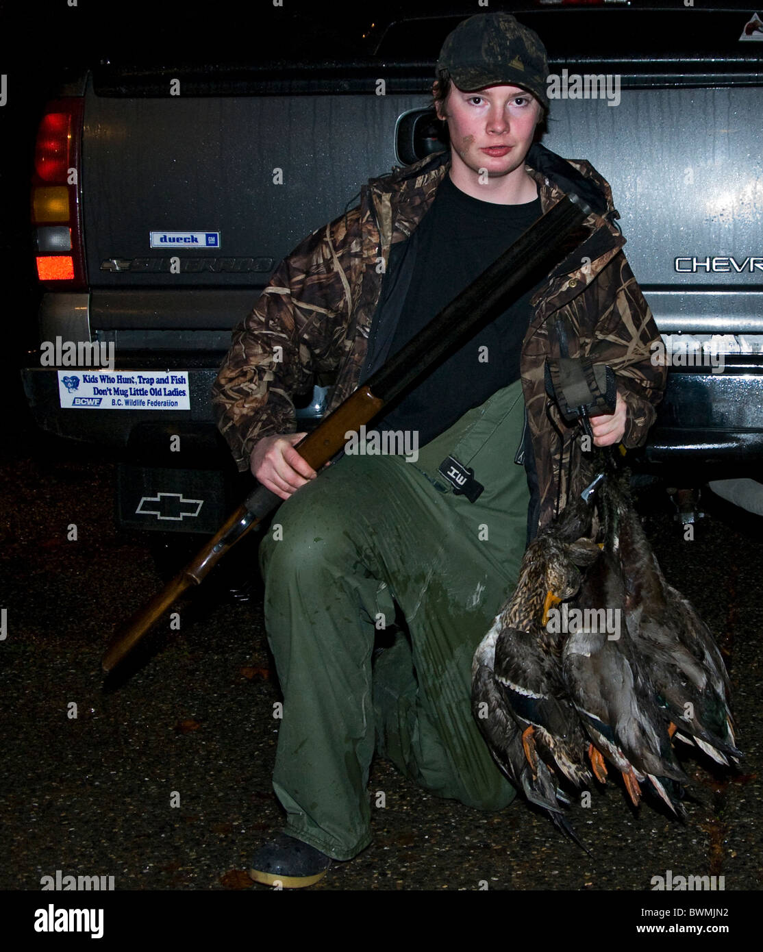 Adolescente sosteniendo una escopeta de doble cañón y con su cosecha de un viaje de caza de patos. Foto de stock