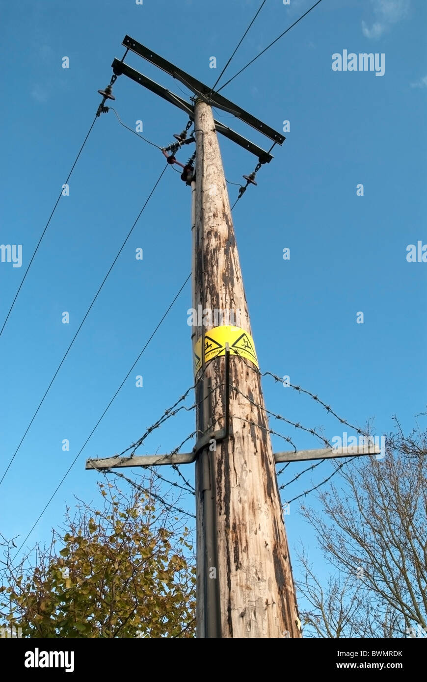 Poste de madera de los postes de la electricidad con las líneas eléctricas  y alambre de espino alrededor para evitar Subir Fotografía de stock - Alamy