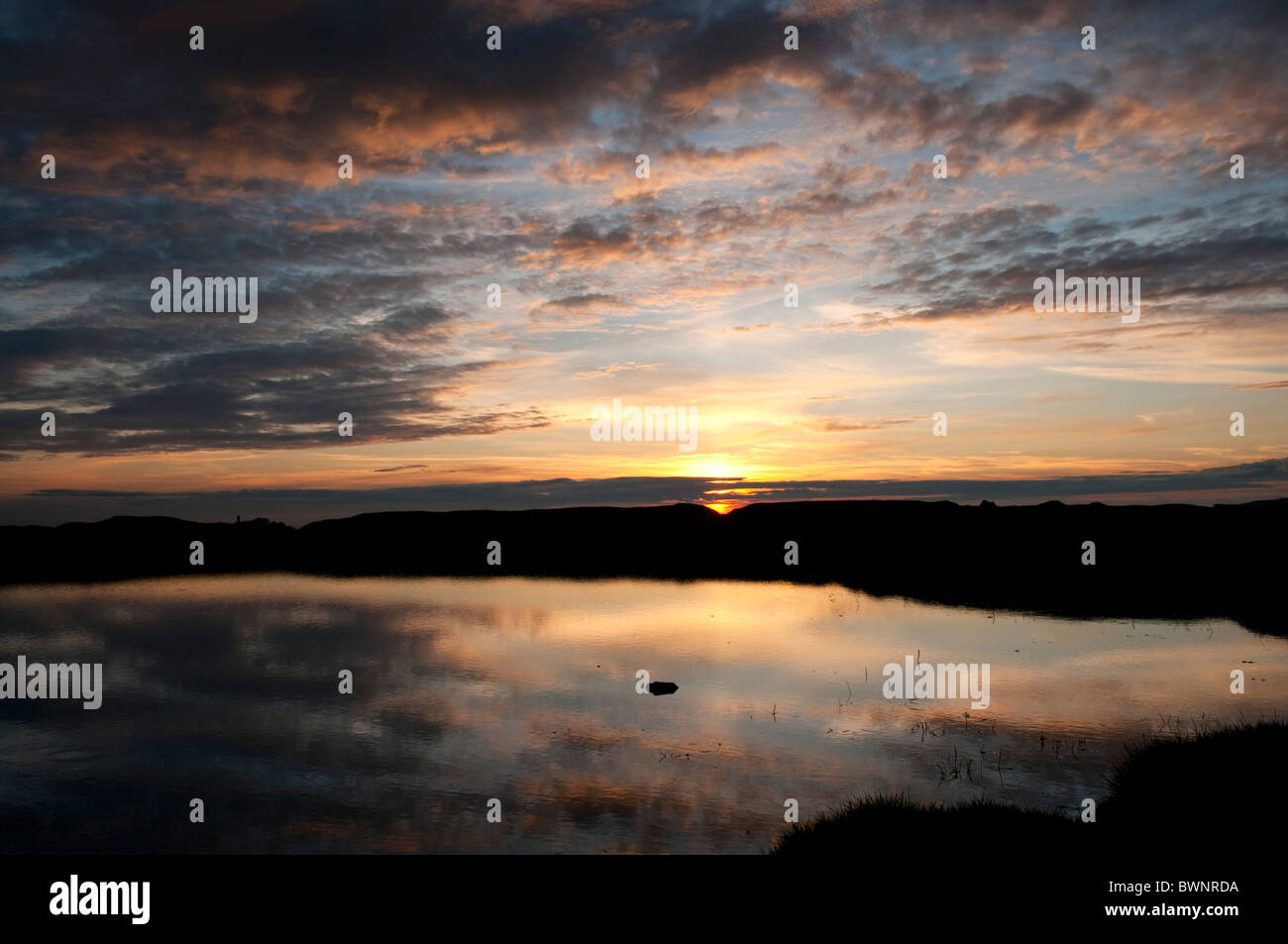 Reflexiones de la puesta de sol y nubes en el agua del estanque en Dartmoor Devon, Reino Unido Foto de stock