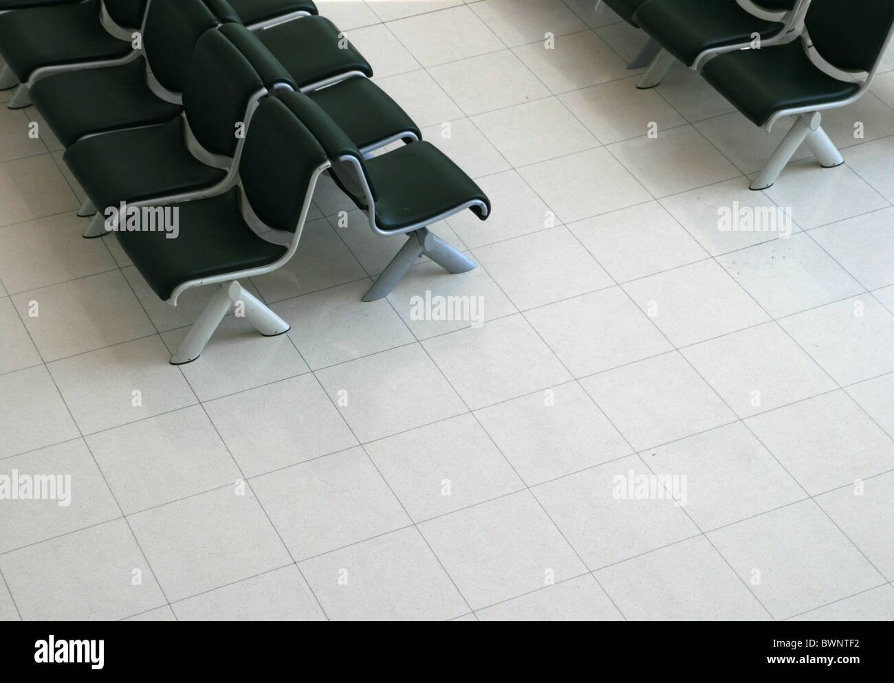 Zona de espera con asientos acolchados negro luz y suelo de azulejos desde arriba Foto de stock