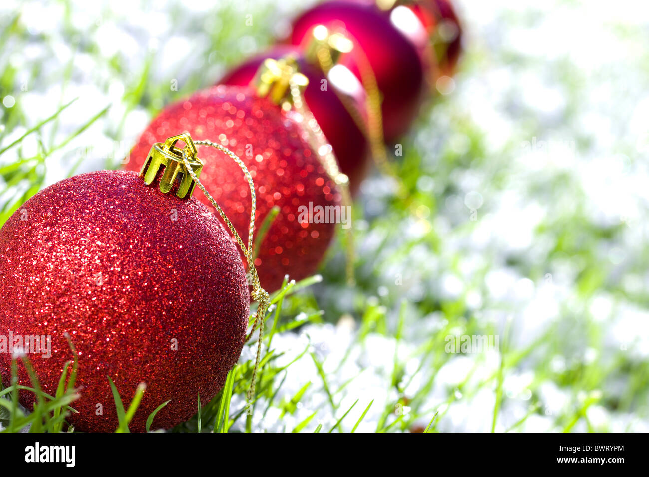 Fila de bolas de Navidad con nieve y la hierba congelada se centran en primera bola Foto de stock