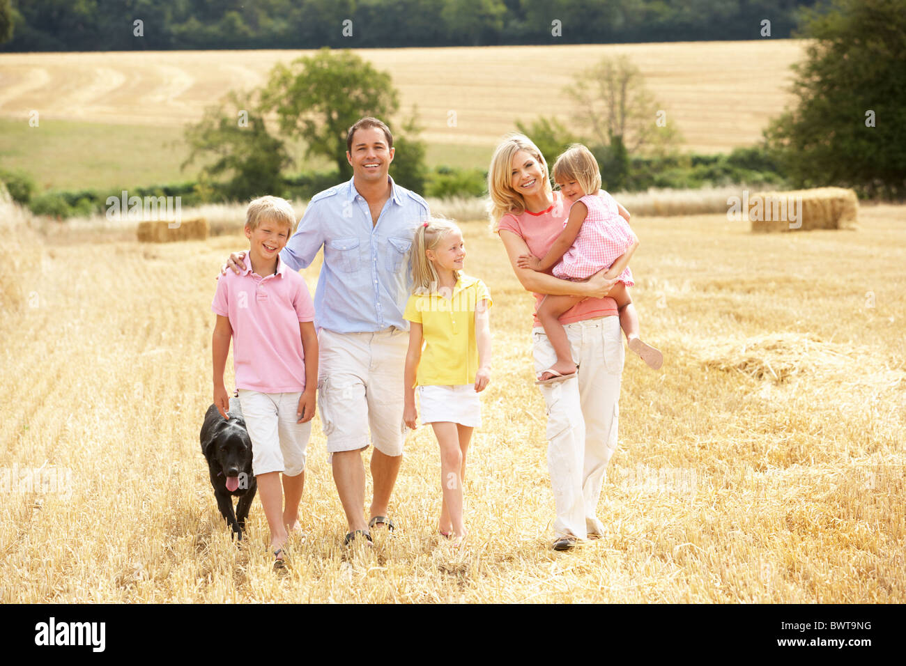 Familia caminando juntos a través de verano campo cosechado Foto de stock
