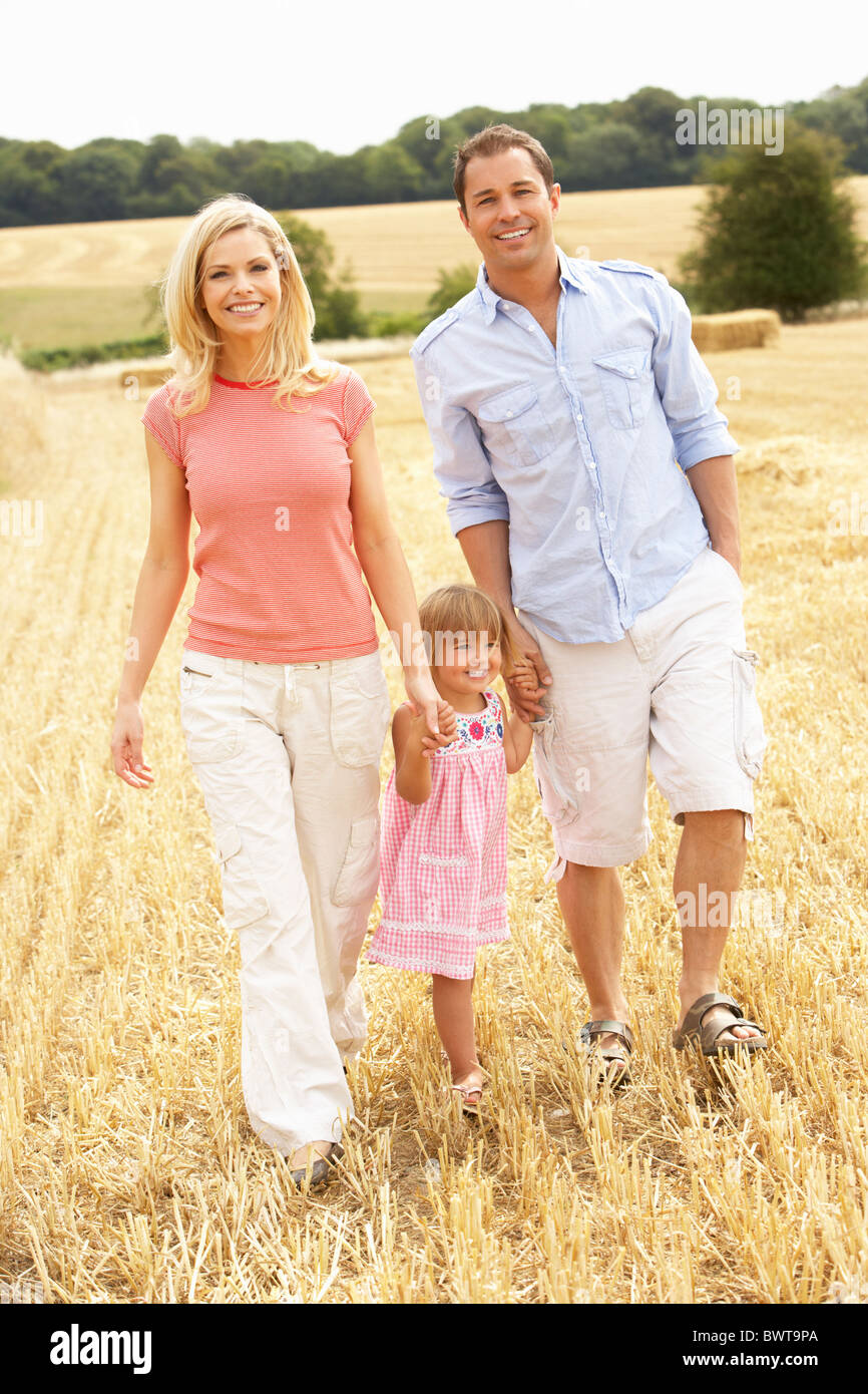 Familia caminando juntos a través de verano campo cosechado Foto de stock