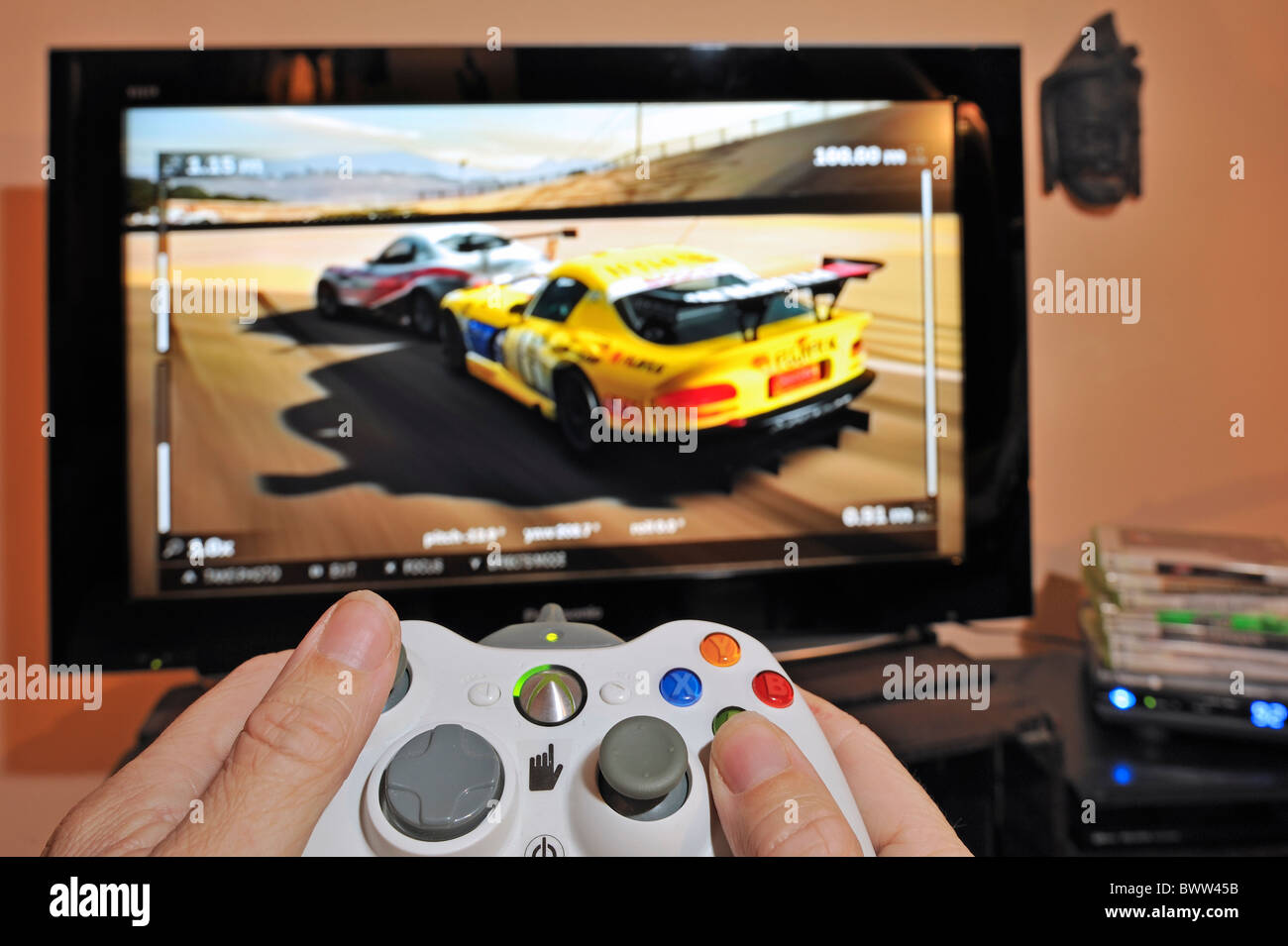 Manos sosteniendo el controlador en frente de una pantalla de televisión mostrando los coches en el juego de carreras Foto de stock