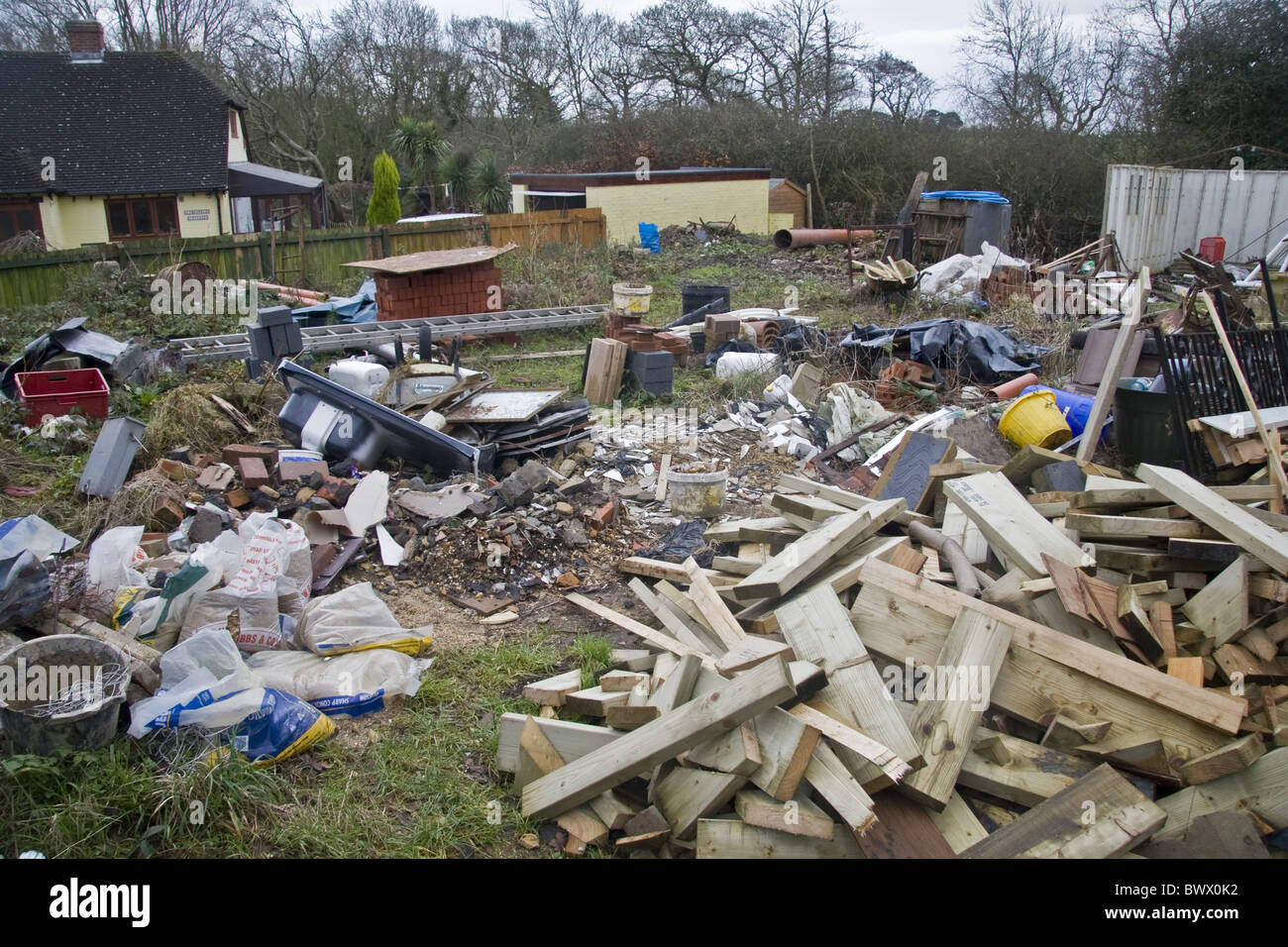 Caos desordenado desorganizado lío perezoso jardín patio basura basura constructores Milford sobre mar Hampshire Inglaterra contaminación contaminar Foto de stock