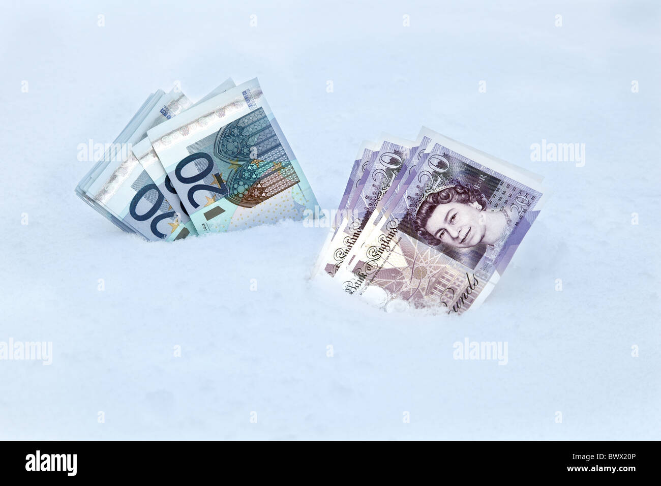 Dos montones de dinero en la nieve, 20€ y 20€ al lado de notas Foto de stock