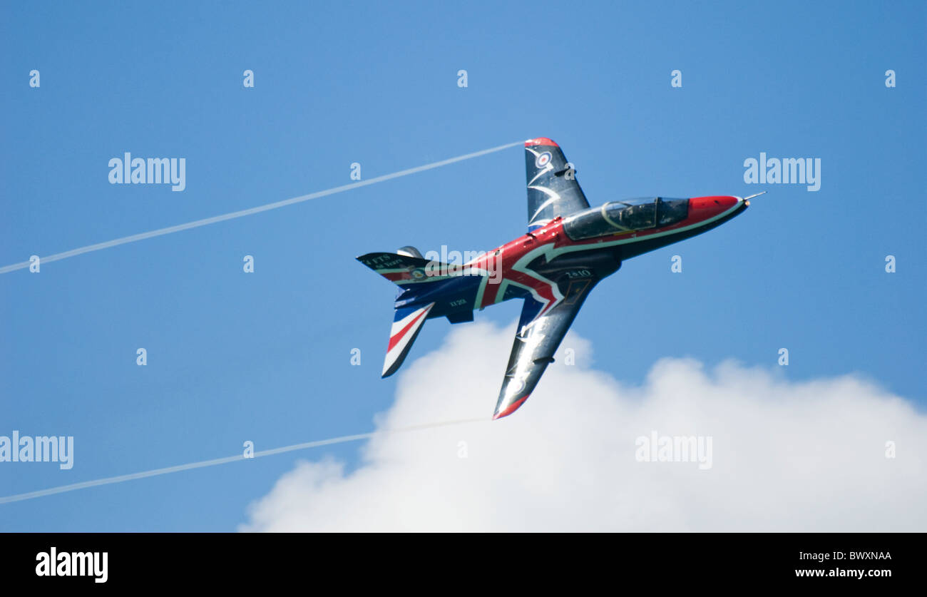 Visualización de la RAF Hawk volando hacia la derecha de shot - marcas superior aparece detrás del humo de las puntas de las alas y el cielo azul y la nube Foto de stock