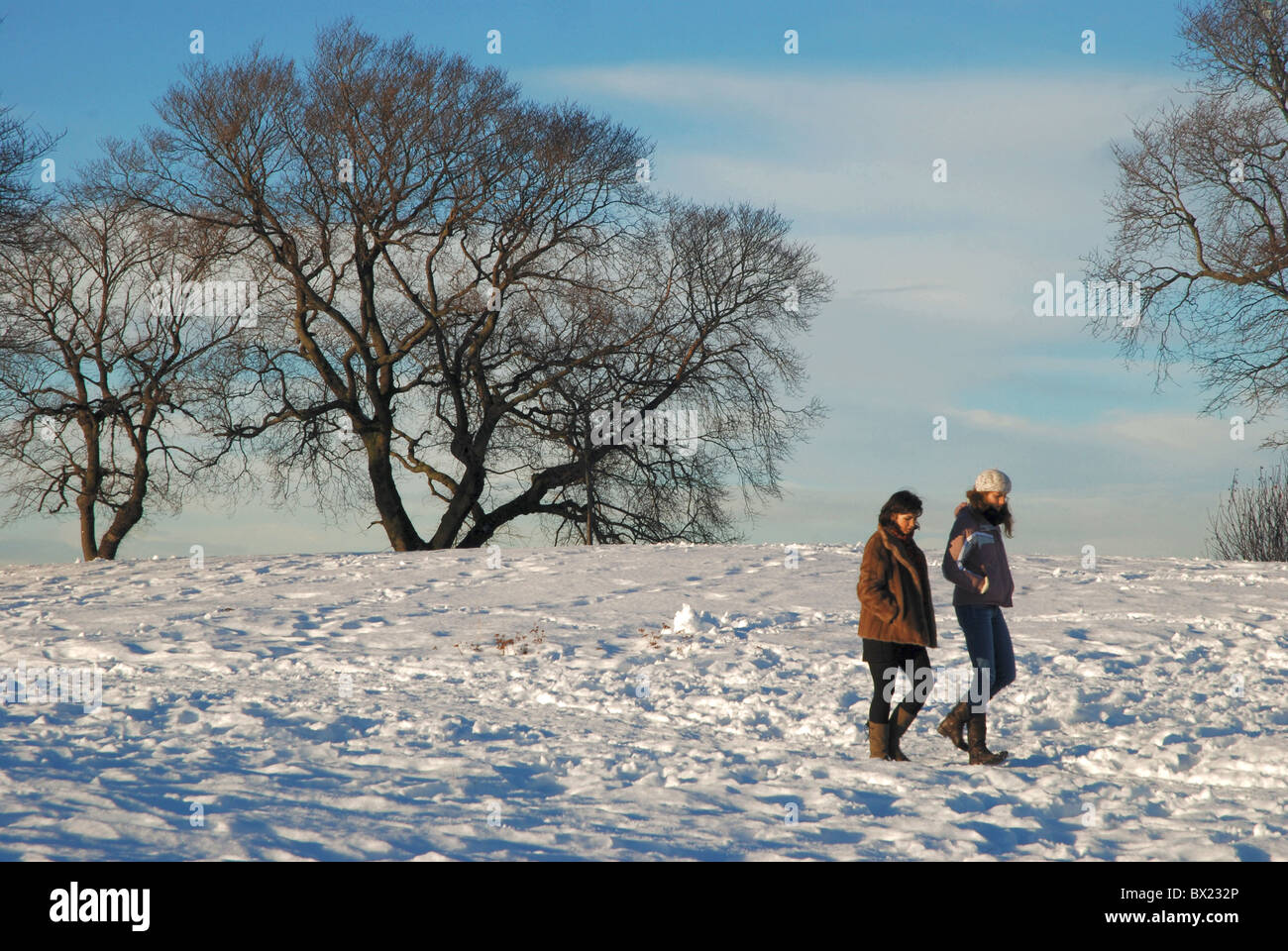 Dos mujeres disfrutando de una caminata en la nieve en Calton Hill, Edimburgo, Escocia, Reino Unido. Foto de stock