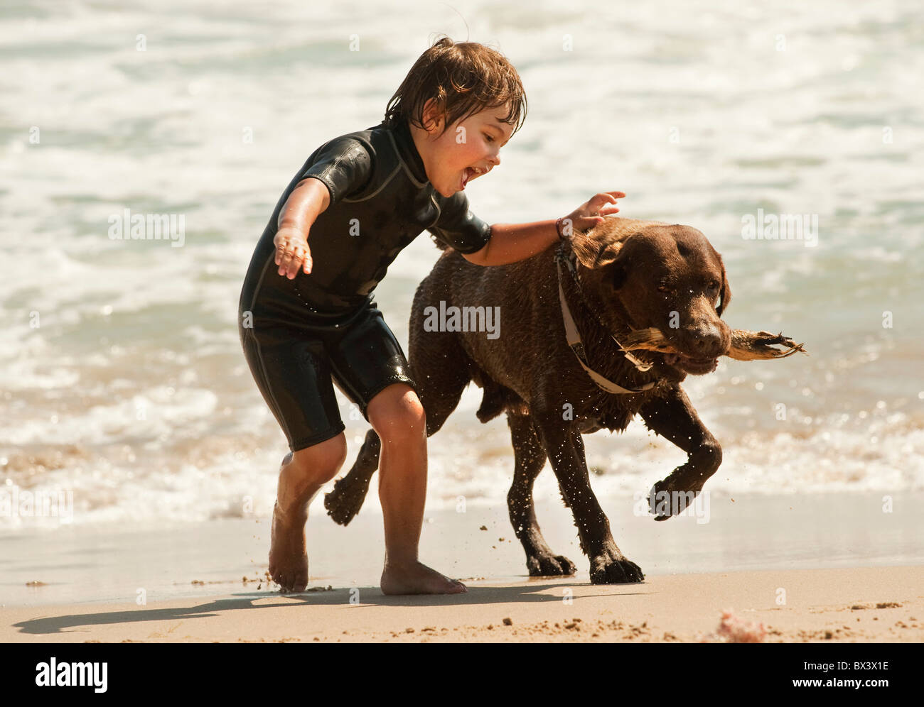 Un chico corre con un perro en Dos Mares playa en frente del Hotel Dos Mares, Tarifa, Cádiz, Andalucía, España Foto de stock