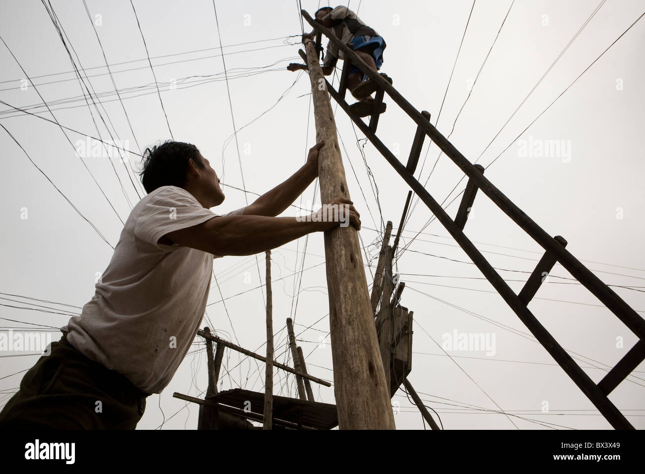 Los hombres de reparación eléctrica enmarañada de líneas en San Juan de Miraflores, Lima, Perú. Foto de stock