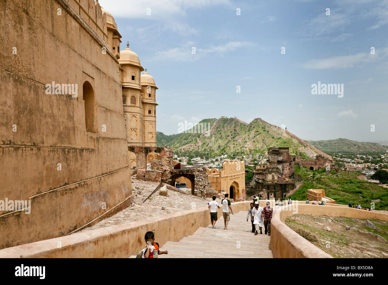 Los turistas que caminan escaleras arriba y abajo del Fuerte Amber Palace, Jaipur, Rajasthan, India, con colinas en el fondo. Foto de stock