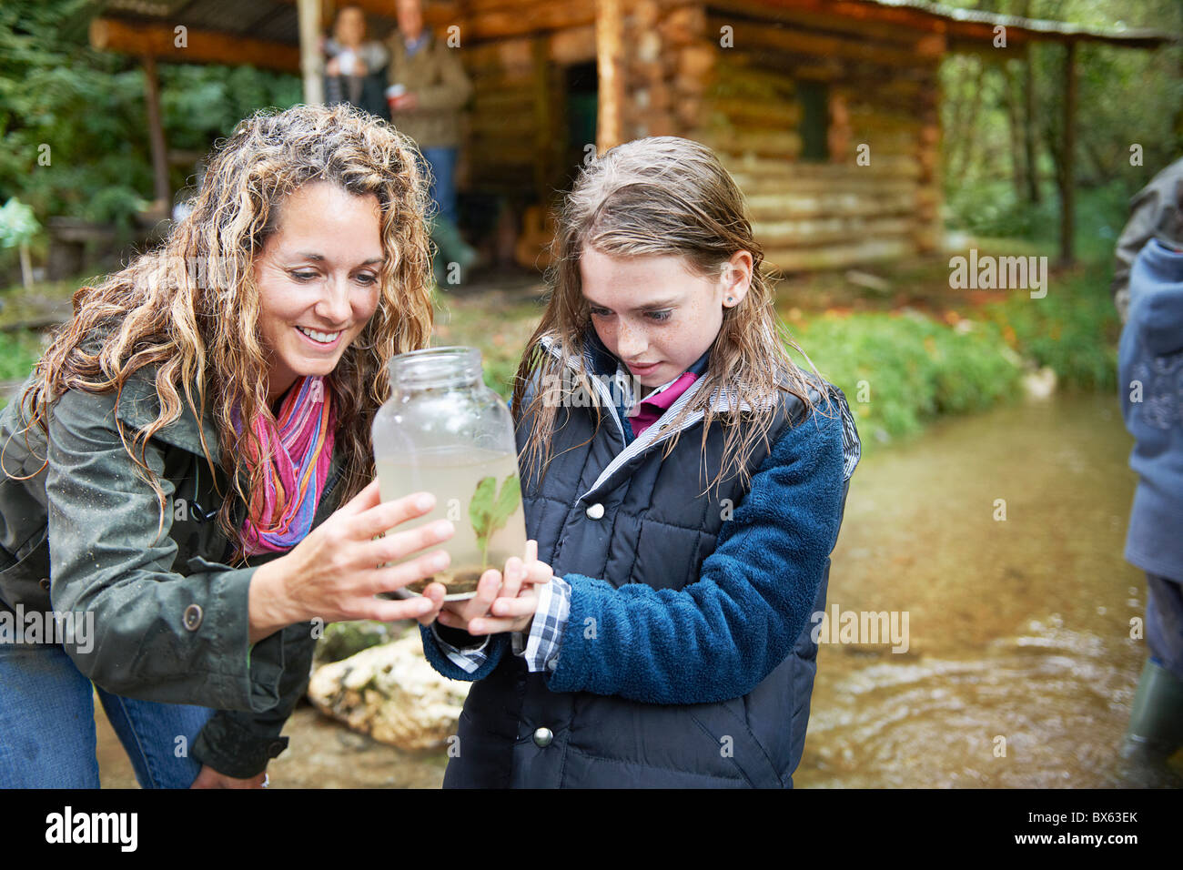 Madre e hija examinar insecto en jar Foto de stock