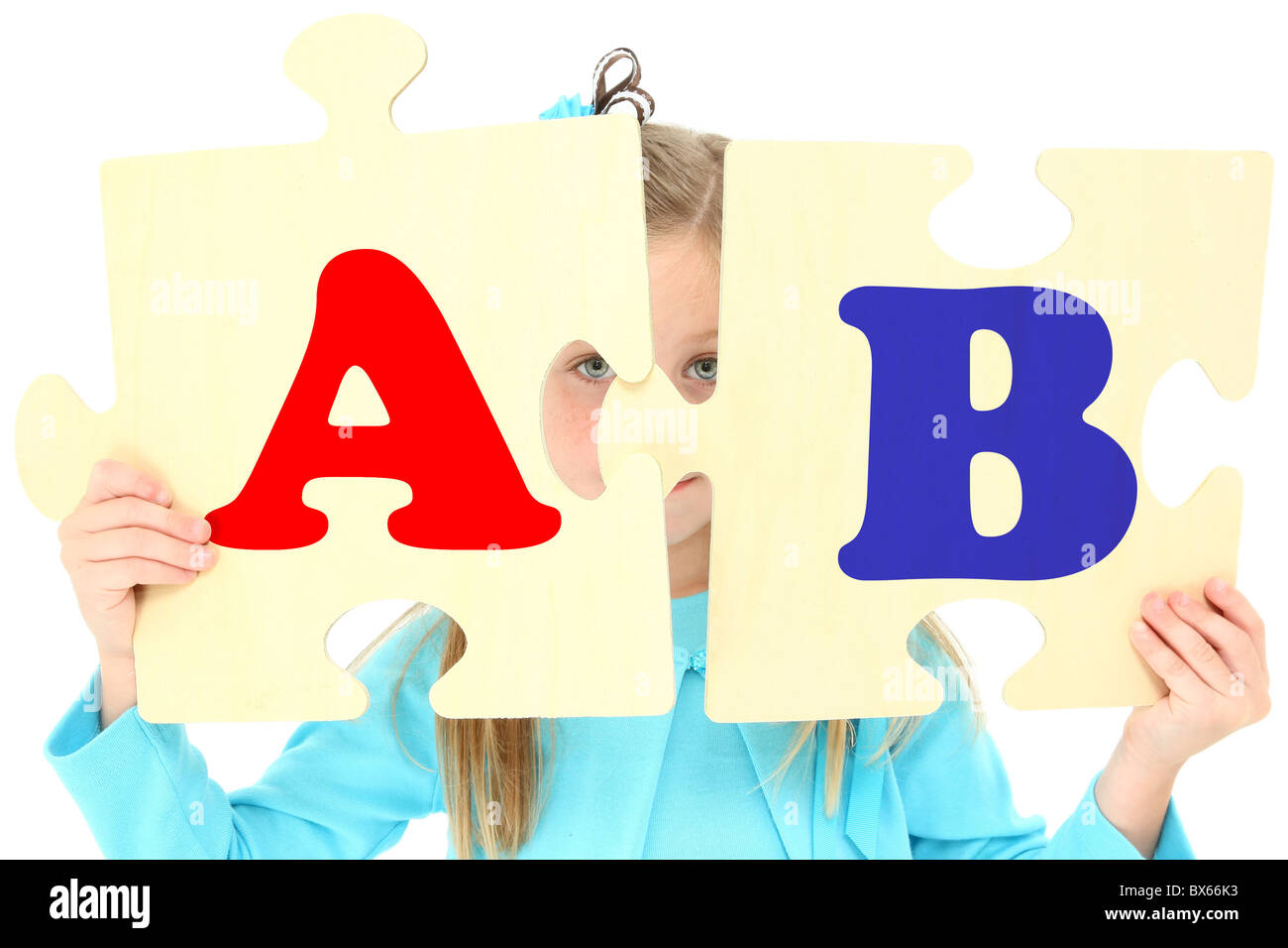 Cinco años adorable chica americana mantiene grandes piezas de puzzle alfabeto sobre fondo blanco. Foto de stock
