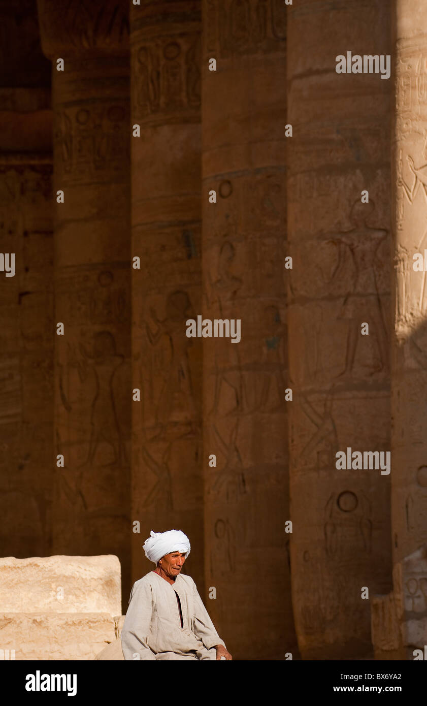 Un solitario hombre egipcio en la vestimenta sentado y vagar alrededor de los pilares ruinas del templo egipcio de Ramsés II Fotografía de stock - Alamy