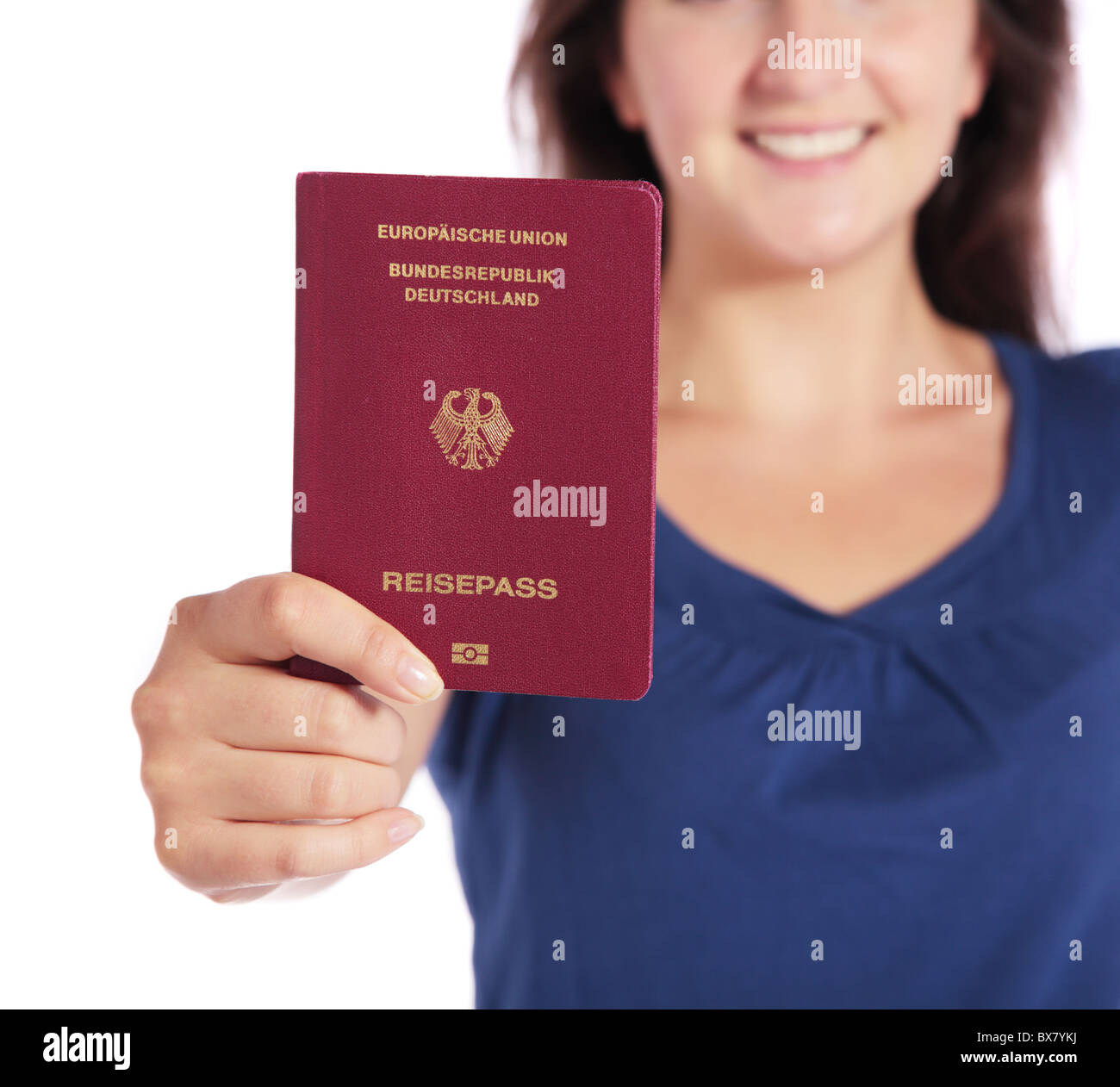 Atractiva mujer joven sosteniendo un pasaporte alemán. Todas aisladas sobre fondo blanco. Foto de stock