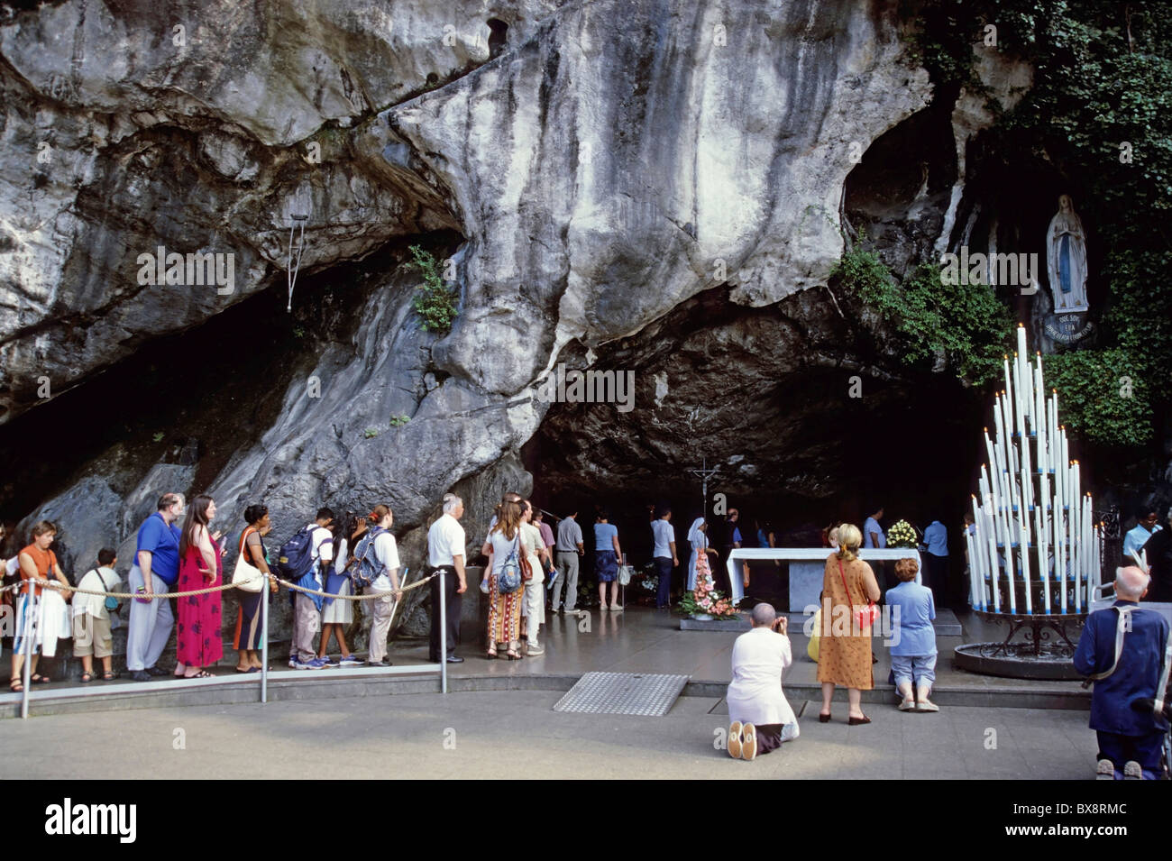 Lourdes, Francia : peregrinos que visitan la estatua de Nuestra Señora de Lourdes en la gruta de Massabielle, en Lourdes, Francia. Foto de stock