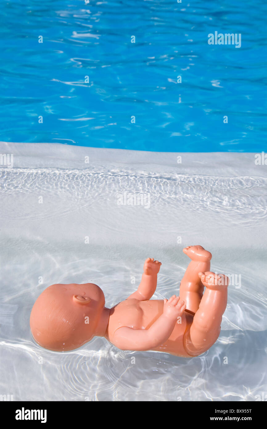 Muñeca desnuda bebé flotando en una piscina de color azul Foto de stock
