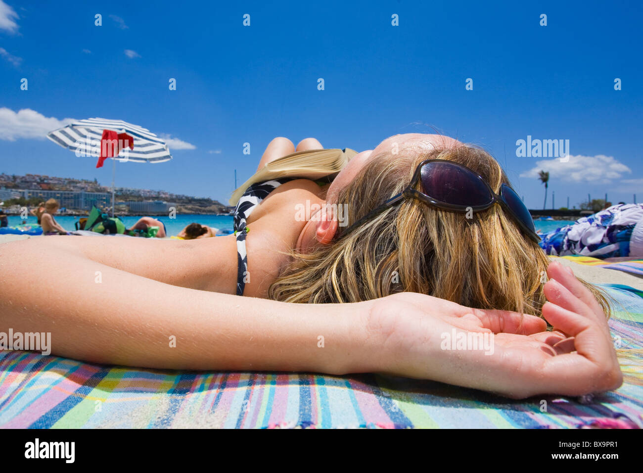 Mujer tomando el sol en una playa en España. La playa de Amadores en Gran Canaria. Foto de stock