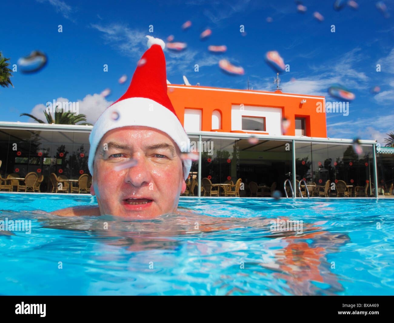 Nadador sonriente vistiendo un gorro de Papá Noel. Gotas de agua sobre el cristal de la cámara, dar esta toma un aspecto único. Foto de stock