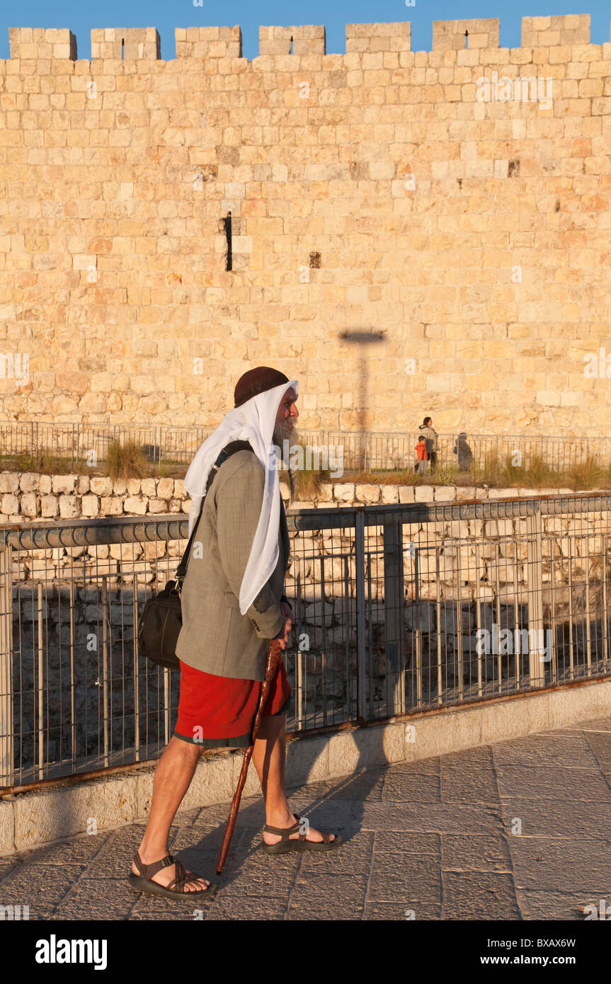 El hombre en la oriental exótico ropa a la puerta de Jaffa de la ciudad con murallas en bkgd Foto de stock
