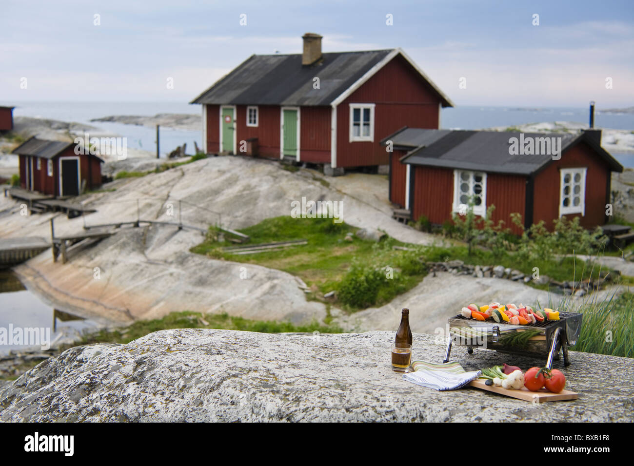 Barbacoa con verduras en roca con casas en segundo plano. Foto de stock
