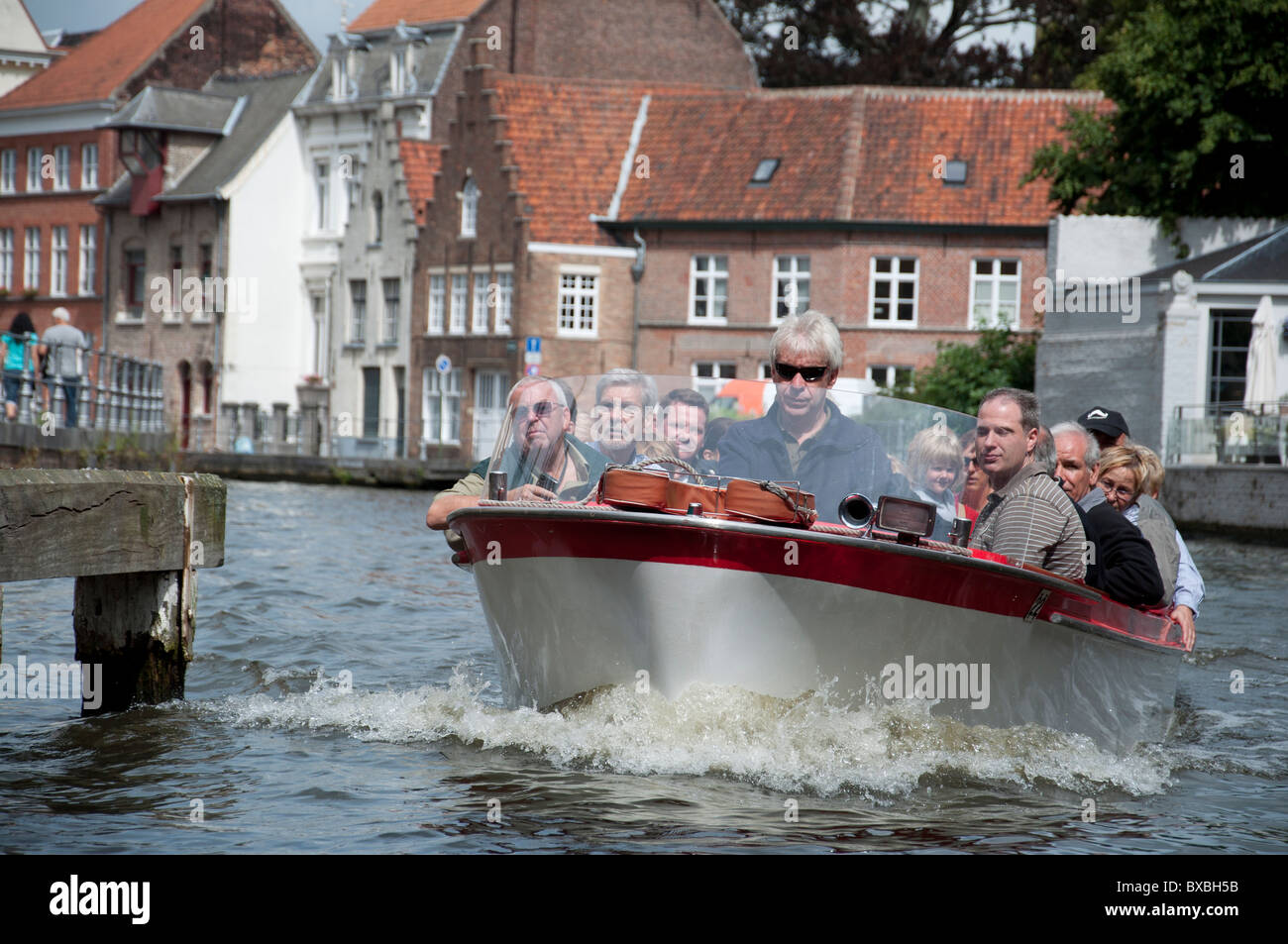 Un crucero Barco llevando pasajeros en un tour de Brujas y sus alrededores en Brujas, Bélgica. Foto de stock
