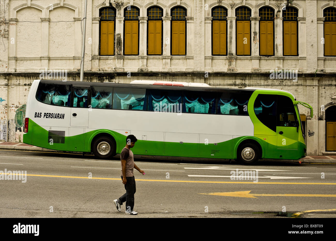 Un hombre que camina más allá de un entrenador de autobús en una calle de Kuala Lumpur. Foto por Gordon Scammell Foto de stock