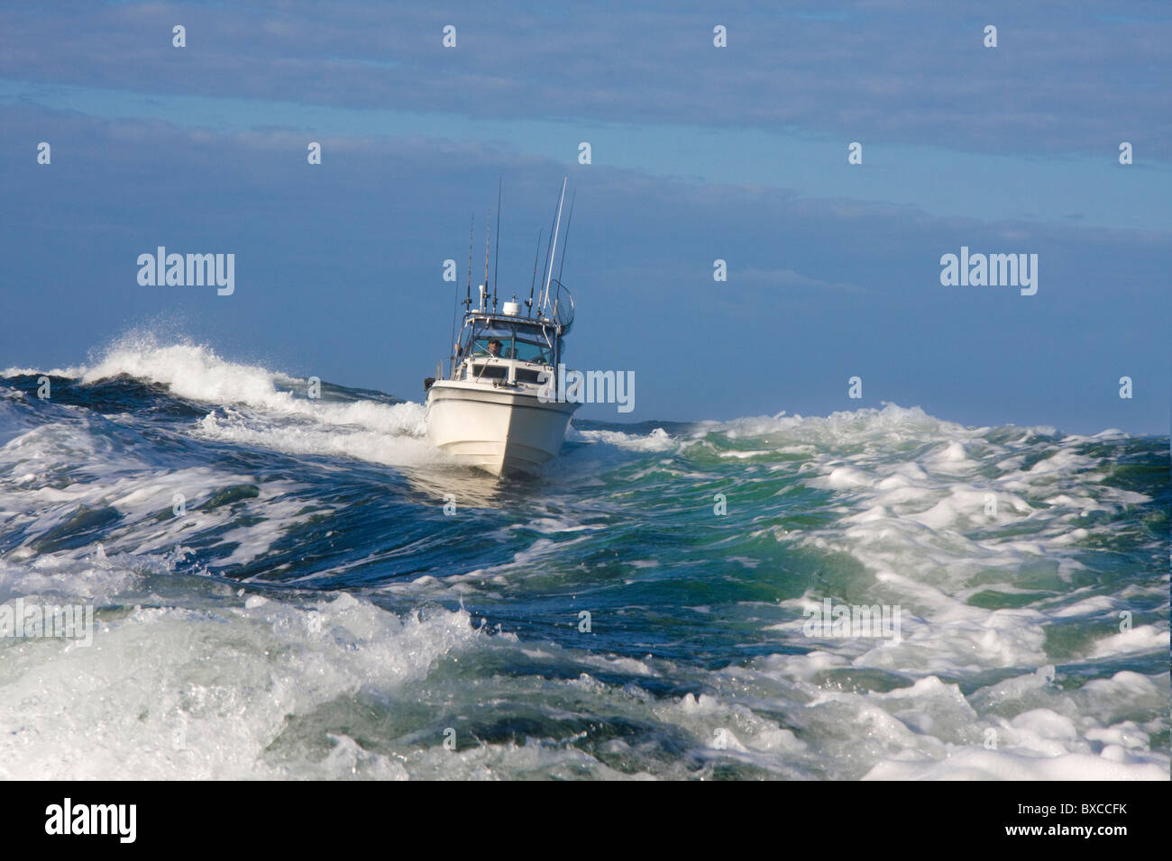 Embarcaciones de recreo Pesca Deportiva estilo barco navegando por el mar embravecido, cresterías una gran ola acercándose a la cámara en una mañana brillante. Foto de stock
