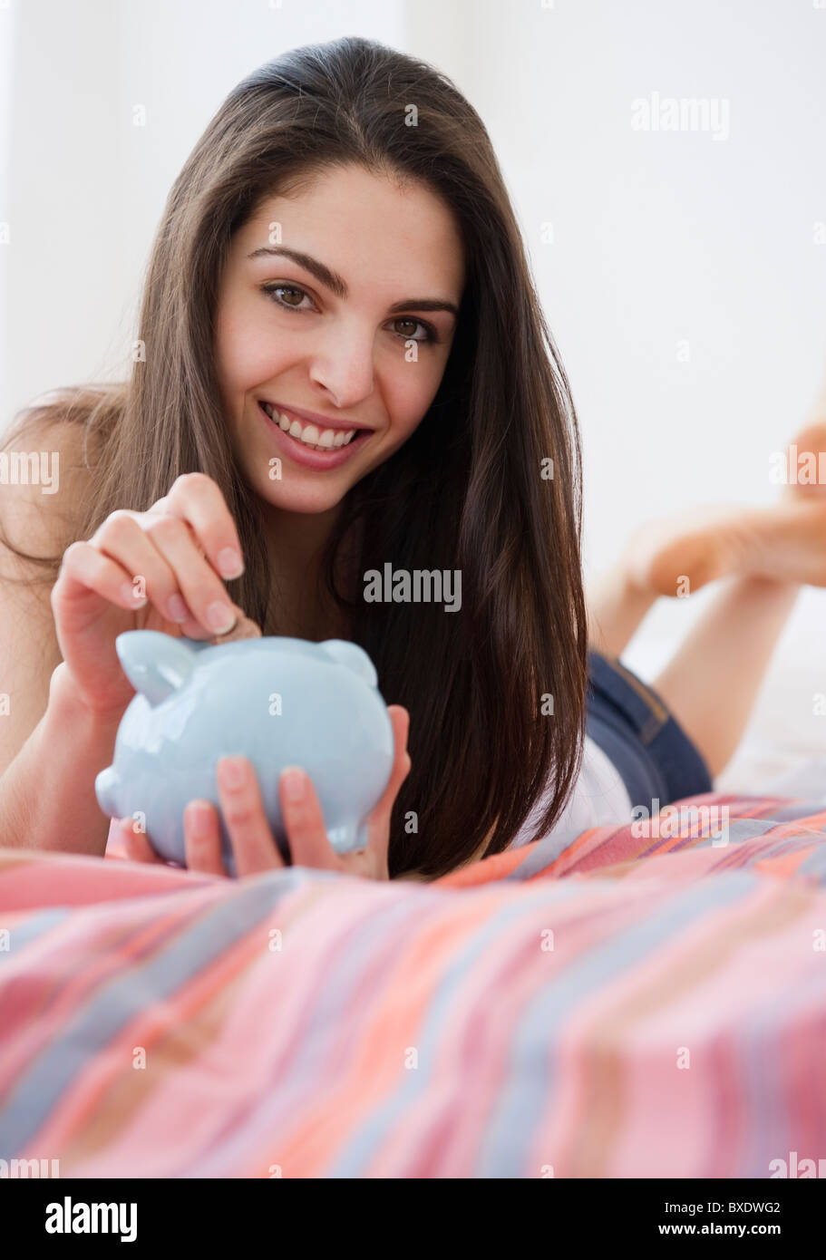 Mujer poner monedas en la hucha Foto de stock