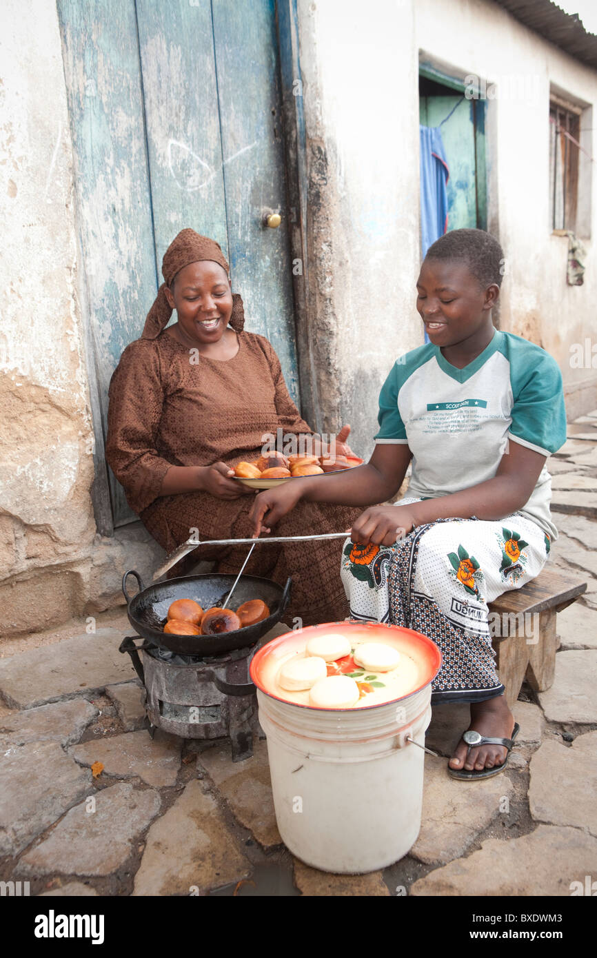 Una joven mujer cocina mandazi (buñuelos) en las calles de Dodoma, Tanzania, África Oriental. Foto de stock