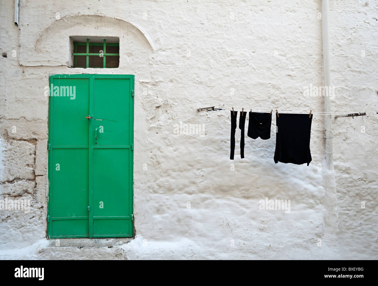 Puerta panted verde y secado de ropa en el tendedero, Ostuni, Puglia, Italia Foto de stock