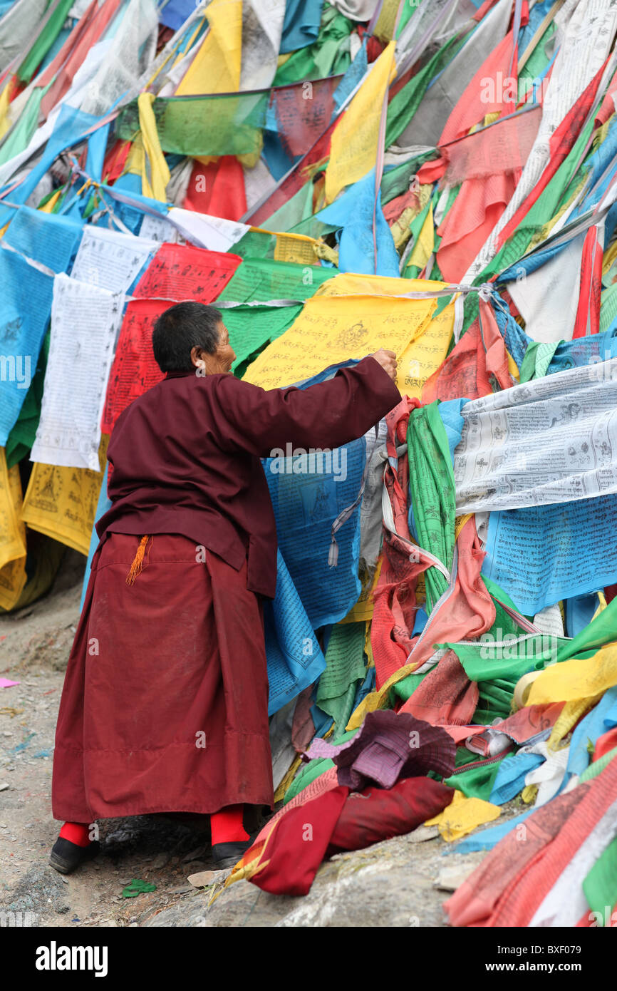 Monje con banderas de oración en el exterior camino peregrino o Lingkhor alrededor de Iron Mountain en Lhasa, Tibet (Región Autónoma del Tíbet, China. Foto de stock