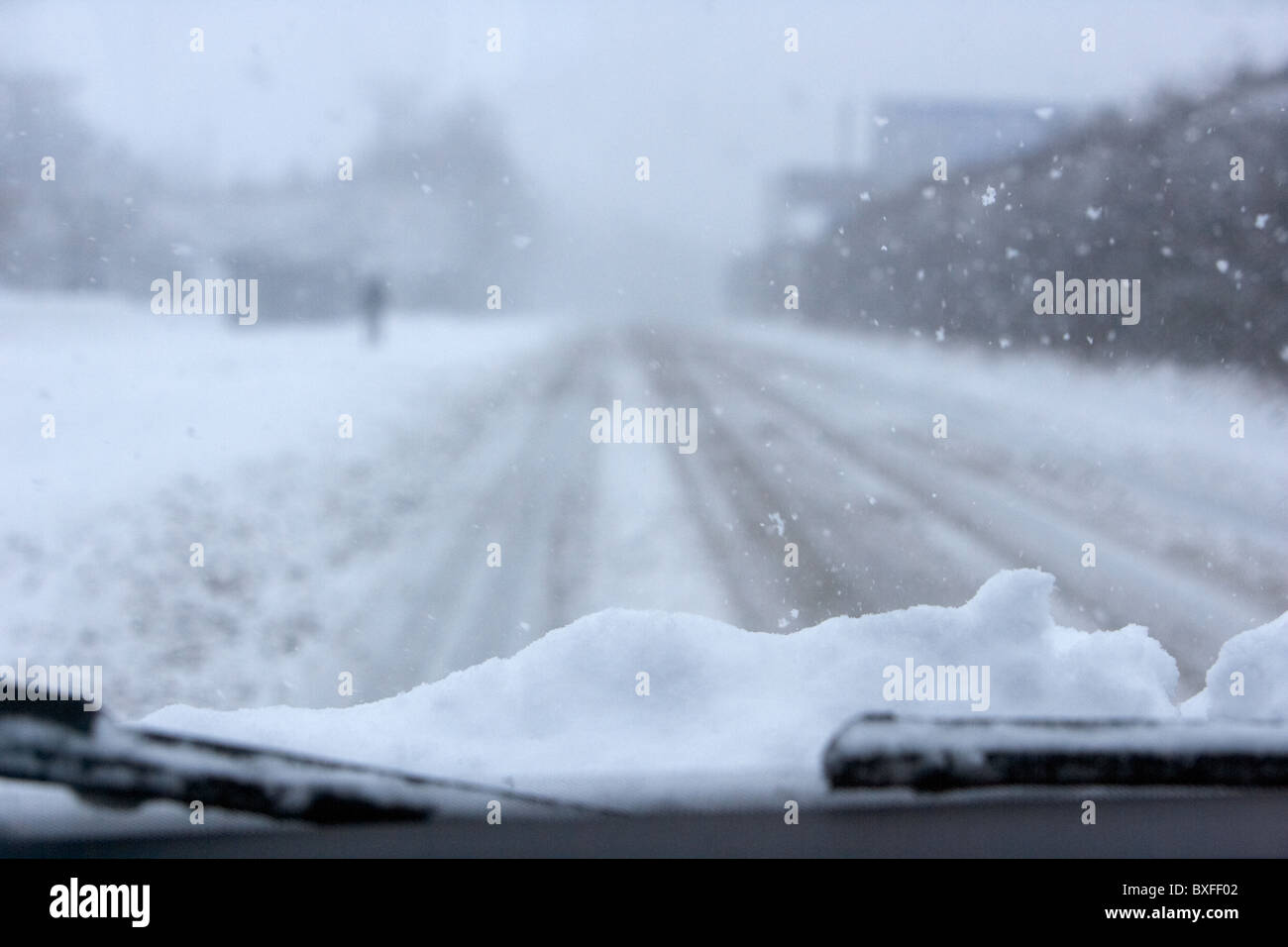 Coche con nieve sobre el capó circulando por una carretera congelada frío inviernos fríos con nieve en un día frío clima invernal nevando carreteras Belfast, Irlanda del Norte Foto de stock