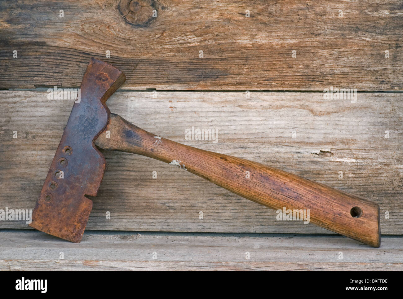 Herramienta antigua de hacha de martillo de guijarros de hierro apoyada en un estante de madera antiguo. Foto de stock
